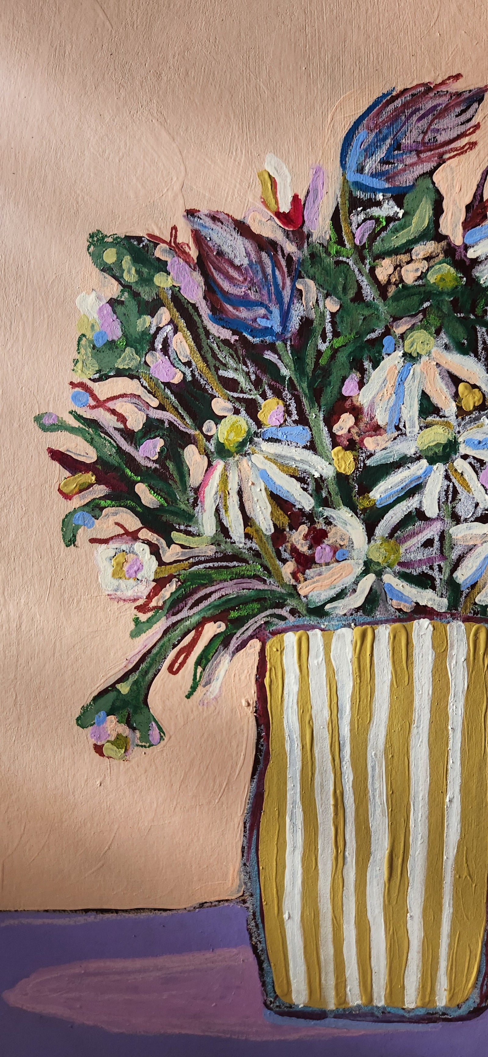 Colorful floral arrangement in a striped vase against a beige background