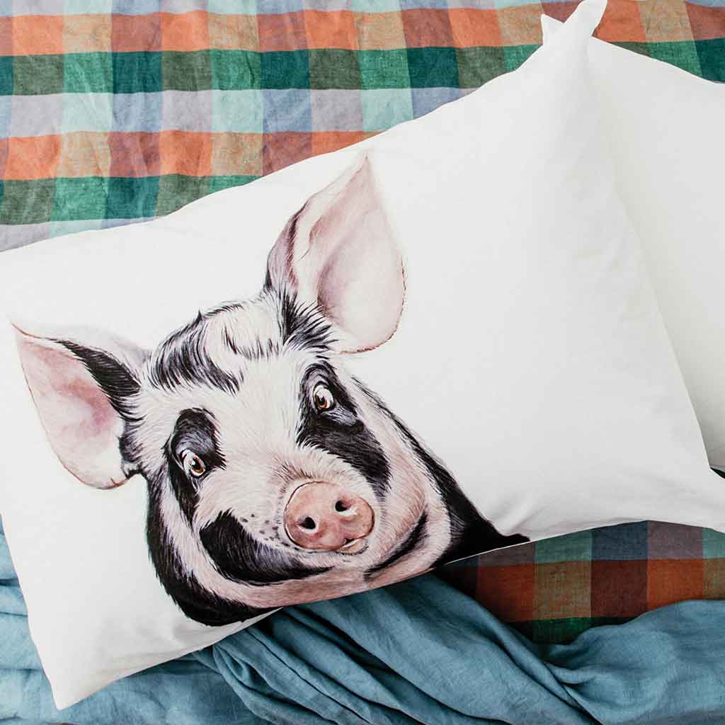 pig artwork cotton pillowcase on bed with gingham sheets