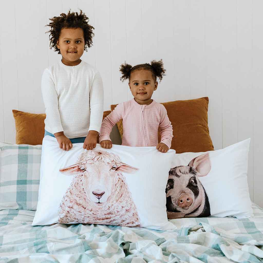 young girls standing on bed with sheep and pig artwork cotton pillowcases